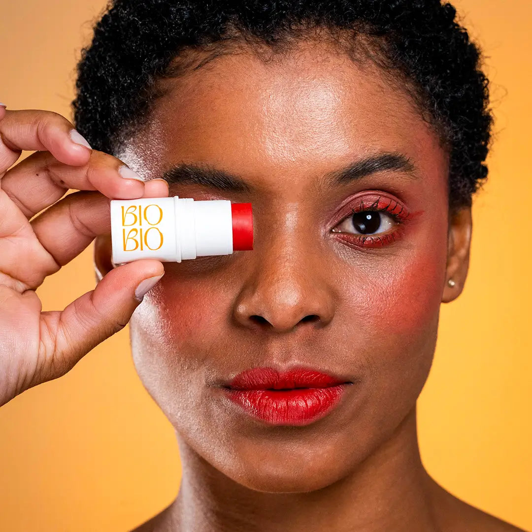 Modelo de pele negra aplicando o BBS Romã da BioBio como sombra, blush e batom