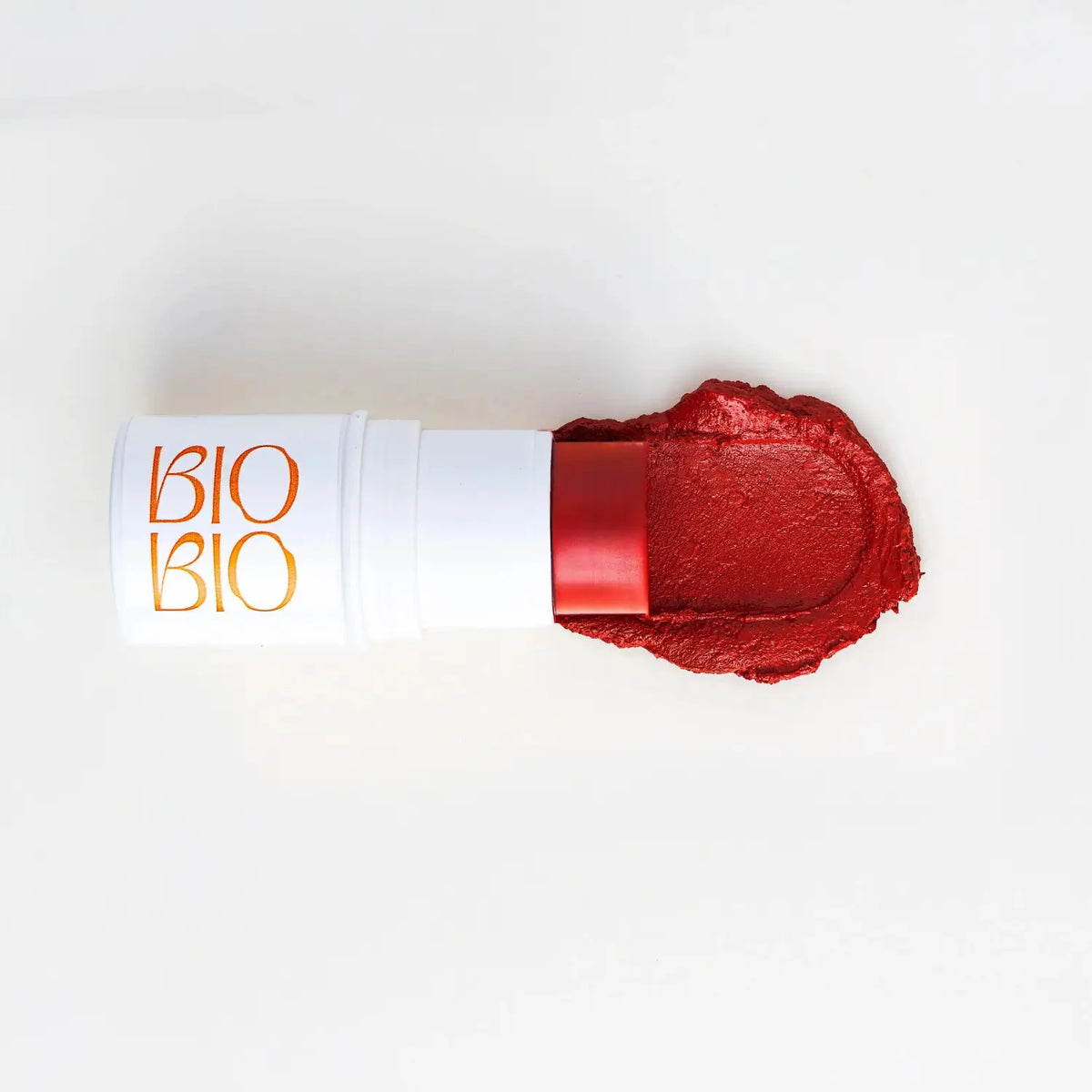 Bastão BBS BioBio Romã ao lado de swatch cremoso vinho-romã, mostrando a textura pigmentada