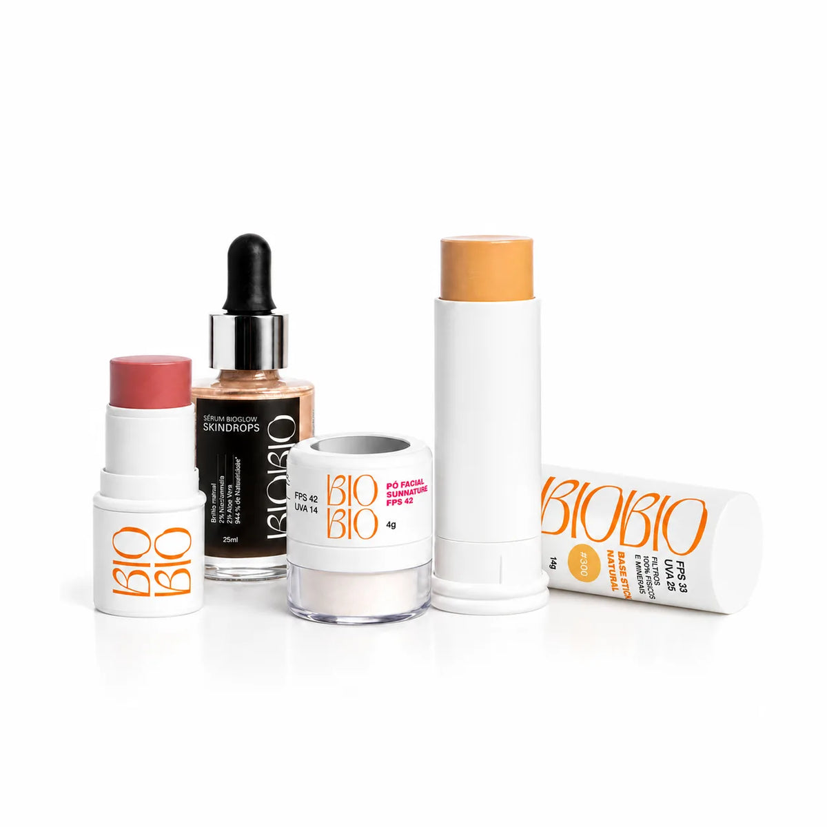 Kit Glow Protegido da BioBio: o BBS blush, batom e sombra FPS 63 aberto num tom rosado, o frasco conta-gotas do Sérum Skindrops Bio Glow de 25 ml, o pote do Pó Facial Sunnature FPS 42 de 4 g e a Base Multifuncional em bastão FPS 33 aberta, com a tampa do tom #300 Castanha deitada ao lado, em fundo branco.